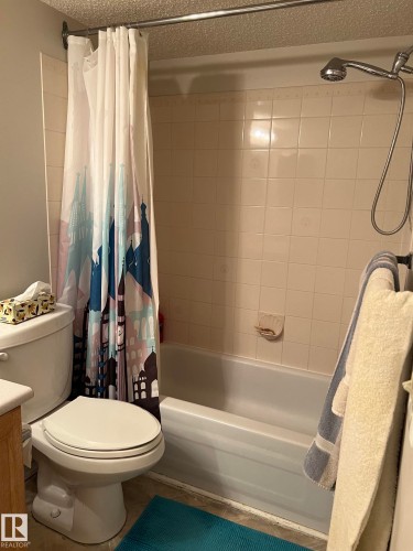 Tub and shower combination featuring a white porcelain tub and light-toned wall tiling - 207 18012 95 Avenue, Edmonton, AB - Indoor Photo Showing Bathroom