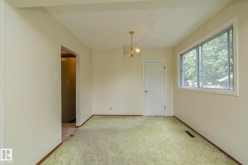 Room featuring light-colored walls and green patterned carpeting - 5608 122 Avenue, Edmonton, AB 