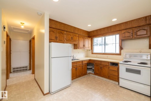 Spacious kitchen featuring wood cabinetry, white appliances, and a window above the sink - 5608 122 Avenue, Edmonton, AB 