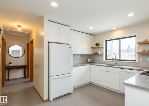 Contemporary kitchen featuring white flat-panel cabinetry, light gray countertops, and a tiled backsplash - 5608 122 Avenue, Edmonton, AB 
