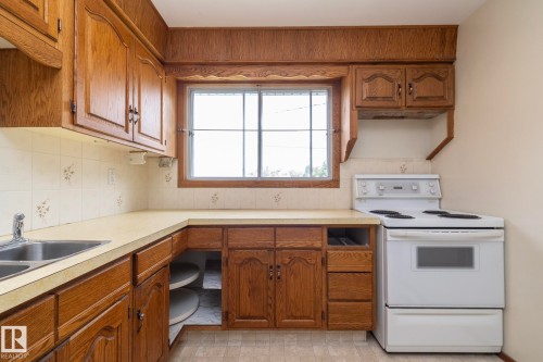 Kitchen featuring wood cabinetry, laminate countertops, and a double basin stainless steel sink - 5608 122 Avenue, Edmonton, AB 