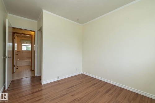 Room featuring wood-finish flooring, light-toned walls, and white trim molding - 5608 122 Avenue, Edmonton, AB 