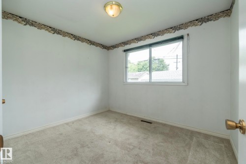 Neutral-toned carpeting and white walls define this room, featuring a double-pane window with a roller shade - 5608 122 Avenue, Edmonton, AB 