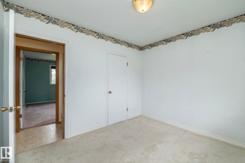 Carpeted room featuring white painted walls and a decorative border - 5608 122 Avenue, Edmonton, AB 