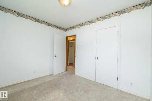 Carpeted interior room with white walls, a decorative wallpaper border, and two white doors - 5608 122 Avenue, Edmonton, AB 