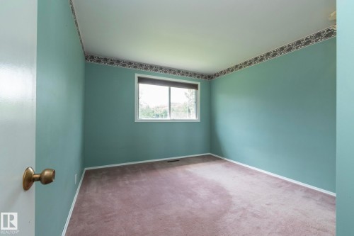 Carpeted room with a double-paned window, baseboard trim, and a decorative border at the ceiling line - 5608 122 Avenue, Edmonton, AB 