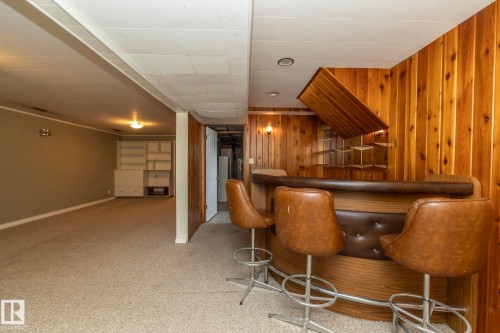 Integrated bar area featuring wood paneling, built-in shelving, and a curved bar - 5608 122 Avenue, Edmonton, AB 