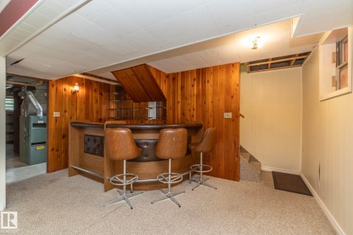 Finished lower level space featuring a built-in bar with wood paneling and a mirrored back wall - 5608 122 Avenue, Edmonton, AB 