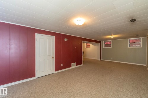 Spacious room featuring textured carpeting, paneled walls, white trim, and ceiling-mounted lighting fixtures - 5608 122 Avenue, Edmonton, AB 