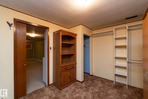 Carpeted room with built-in shelving, a wood-finish bookcase, and a pocket door - 5608 122 Avenue, Edmonton, AB 