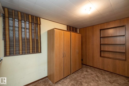 Interior room featuring wood paneling, an integrated wall-mounted bookshelf, and a window with bamboo-style blinds - 5608 122 Avenue, Edmonton, AB 