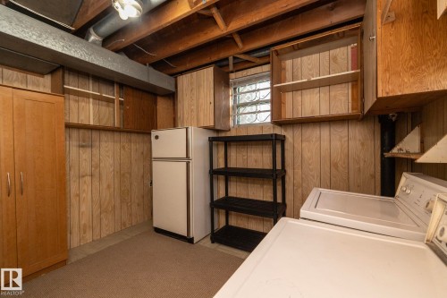 Laundry room with paneled walls, exposed ceiling joists, and a glass block window - 5608 122 Avenue, Edmonton, AB 