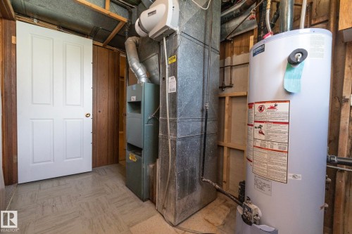 Utility area featuring a hot water heater, furnace, and a white four-panel door - 5608 122 Avenue, Edmonton, AB 
