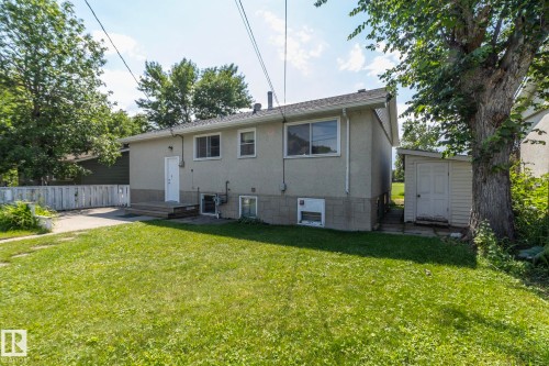 Rear exterior featuring a stucco finish, multiple windows, and a white entry door - 5608 122 Avenue, Edmonton, AB 
