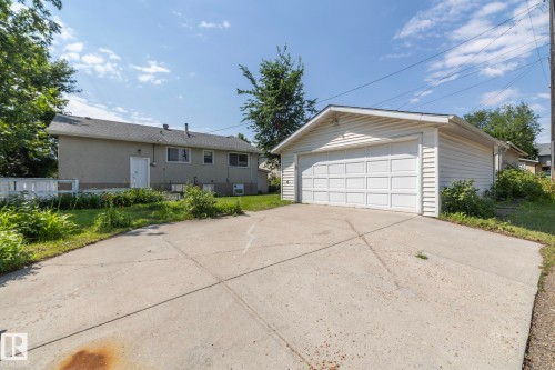 Detached two-car garage with a concrete driveway, white paneled garage door, and vinyl siding - 5608 122 Avenue, Edmonton, AB 