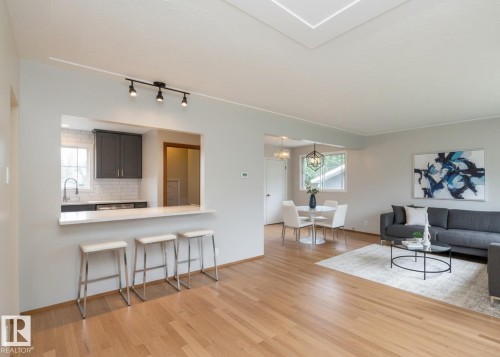 Open-concept living area with wood-finish flooring, a kitchen pass-through with breakfast bar, and a skylight - 5608 122 Avenue, Edmonton, AB 
