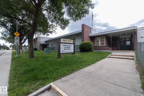 Brick facade building with a prominent entrance featuring dual dark doors and a covered walkway - 5608 122 Avenue, Edmonton, AB 