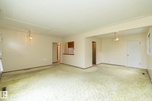 Spacious interior featuring neutral wall tones and textured carpeting - 5608 122 Avenue, Edmonton, AB 