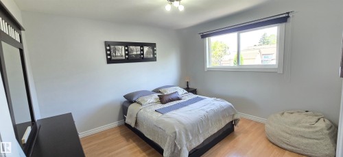 Light-filled room featuring a large window, light-toned walls, and wood-finish flooring - 4233 49 Street, Vegreville, AB - Indoor Photo Showing Bedroom