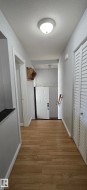 Hallway featuring wood-finish flooring, white baseboards, a flush-mount ceiling light, and white paneled doors - 