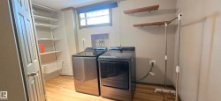 Dedicated laundry area featuring a window, built-in shelving, two wood-finish wall shelves, and wood-finish flooring - 