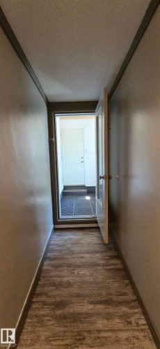 Entryway featuring wood-finish flooring, light-toned wall paint, and a white interior door - 4233 49 Street, Vegreville, AB - Indoor Photo Showing Other Room