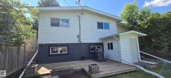 Rear exterior featuring white horizontal siding and a dark lower facade - 