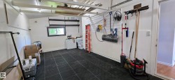 Spacious garage featuring black modular flooring, built-in shelving, an interior window, and track lighting - 