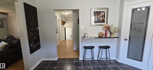 Tiled flooring entry with a built-in shelf and a frosted glass pantry door - 4233 49 Street, Vegreville, AB - Indoor Photo Showing Other Room