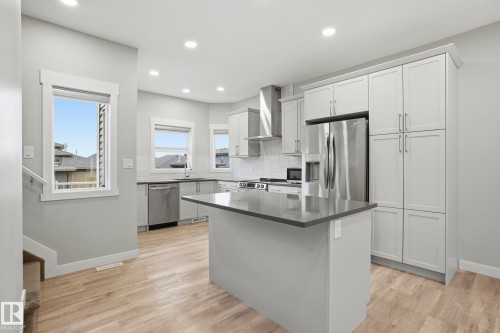 Modern kitchen featuring light gray cabinetry and wood-finish flooring - 36 150 Everitt Dr, St. Albert, AB - Indoor Photo Showing Kitchen With Stainless Steel Kitchen With Upgraded Kitchen