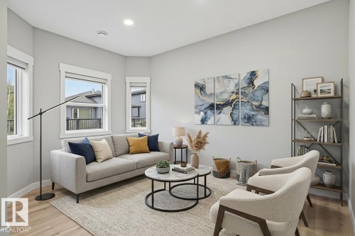 Living area featuring light wood-finish flooring, multiple windows with white trim, recessed lighting, and a built-in shelving unit with dark metal framing and wood-finish shelves - 36 150 Everitt Dr, St. Albert, AB - Indoor Photo Showing Living Room