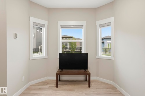 Corner room featuring three windows with white trim, light tone walls, and wood-finish flooring - 36 150 Everitt Dr, St. Albert, AB - Indoor Photo Showing Other Room