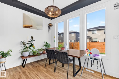 Dining area featuring wood-finish flooring, a contemporary chandelier, and a dark accent ceiling trim - 423 42 Street, Edmonton, AB 