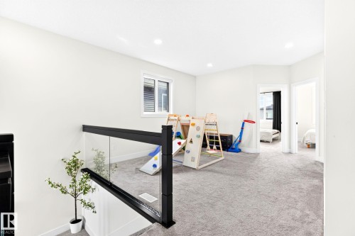 Carpeted upper-level landing featuring a glass and black metal railing, white walls, and recessed lighting - 423 42 Street, Edmonton, AB 