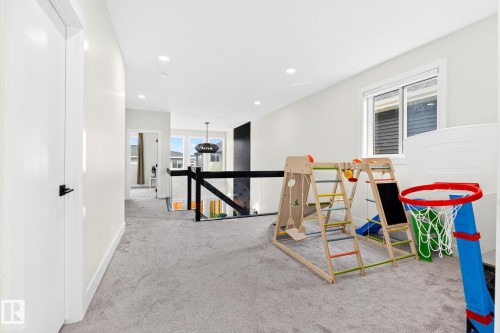 Upper-level landing featuring light gray carpet, recessed lighting, and a modern glass and black metal railing - 423 42 Street, Edmonton, AB 