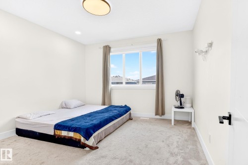 Carpeted room featuring a large window with white trim, a flush-mount ceiling light fixture, recessed lighting, and white walls - 423 42 Street, Edmonton, AB 