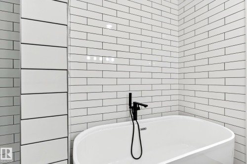 Freestanding bathtub featuring a matte black wall-mounted faucet and handheld spray - 423 42 Street, Edmonton, AB 