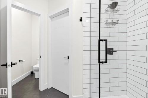 Shower enclosure featuring subway tile surround, clear glass door, and matte black fixtures - 423 42 Street, Edmonton, AB 