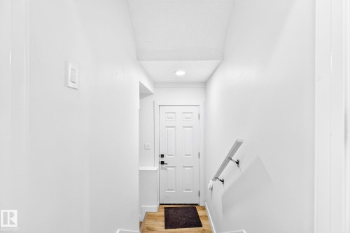 Entryway featuring wood-finish flooring, white paneled door, and a wall-mounted handrail - 423 42 Street, Edmonton, AB 