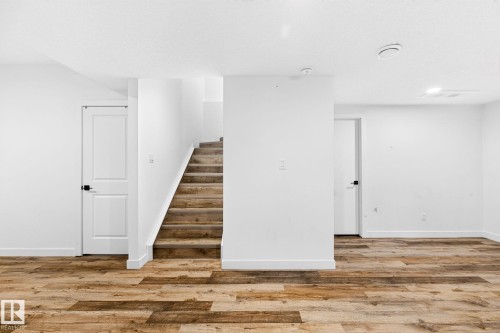 Interior space featuring wood-finish flooring, white walls, and a staircase with wood-finish treads - 423 42 Street, Edmonton, AB 