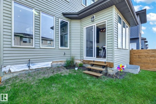 Exterior features a light green siding, multiple large windows, a sliding glass door, and wooden steps - 423 42 Street, Edmonton, AB 