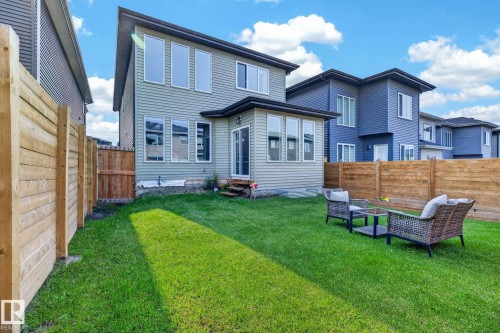 Manicured green lawn featuring a wooden privacy fence, a sunroom extension, and multiple large windows - 423 42 Street, Edmonton, AB 
