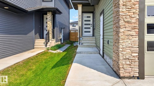 Modern exterior showcasing light green siding and stone veneer accents - 423 42 Street, Edmonton, AB 