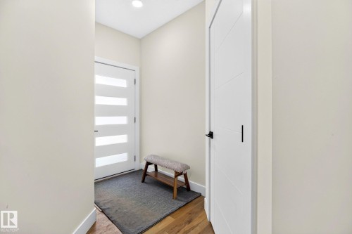 Entryway featuring a white door with frosted glass panels, recessed ceiling lighting, light-toned wall paint, and wood-finish flooring - 423 42 Street, Edmonton, AB 