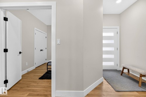Entryway featuring a contemporary front door with frosted glass panels, warm wood-finish flooring, recessed lighting, and crisp white trim - 423 42 Street, Edmonton, AB 