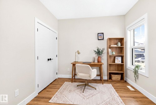 Bright room featuring wood-finish flooring, a large window, a double-door closet with matte black hardware, and light-toned walls with white trim - 423 42 Street, Edmonton, AB 