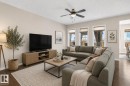 Open-concept living area featuring dark wood-finish flooring, light neutral walls, and a ceiling fan with integrated lighting - 3233 21A Avenue, Edmonton, AB 
