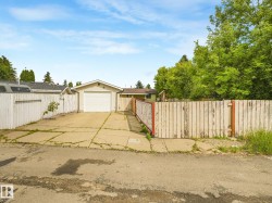 Detached garage with a white overhead door, concrete driveway, and surrounding wood panel fencing - 