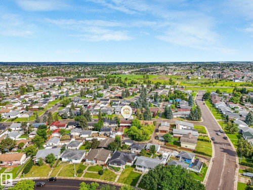 Aerial perspective showcasing a residential neighborhood with a mix of single-story and multi-story homes, mature trees, and ample green spaces - 9315 151 Avenue, Edmonton, AB 