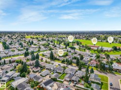 Aerial perspective of a residential community featuring numerous single-family homes, mature trees, and a large green space - 